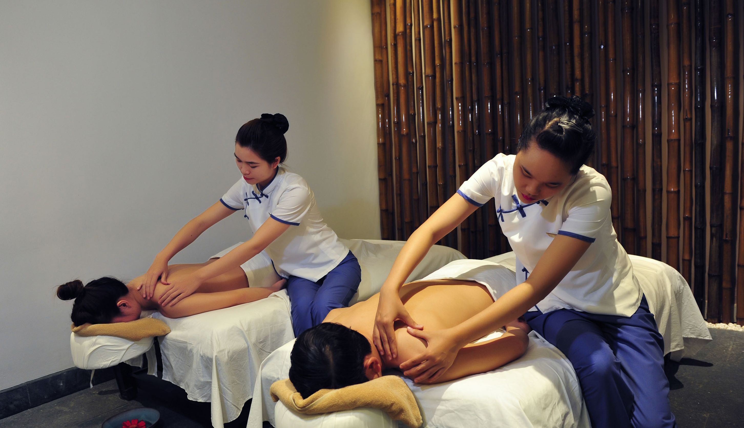 A massage therapy session with three practitioners attending to clients on massage tables.