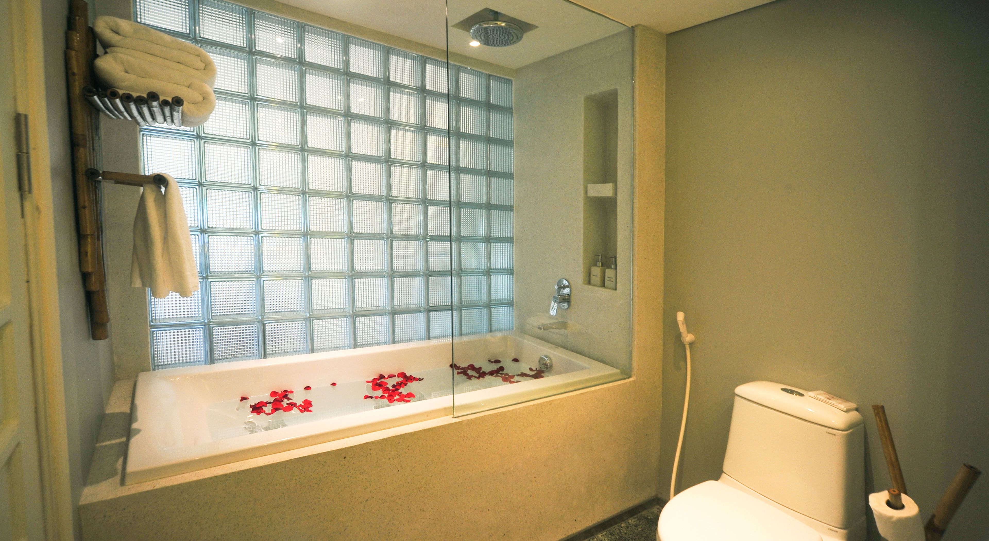 A bathroom with a glass-enclosed bathtub, a toilet, and a shower.