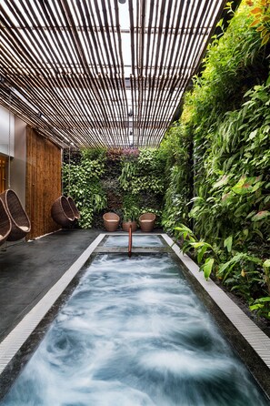 A spa area with a hot tub, bamboo ceiling, and lush greenery. - Alba Spa Hotel (Hue)