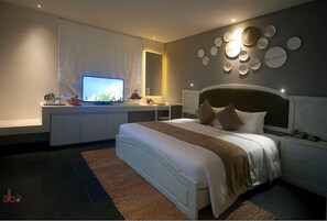 Une chambre moderne avec un grand lit, des tables de chevet, une télévision et des œuvres d’art décoratives au mur.