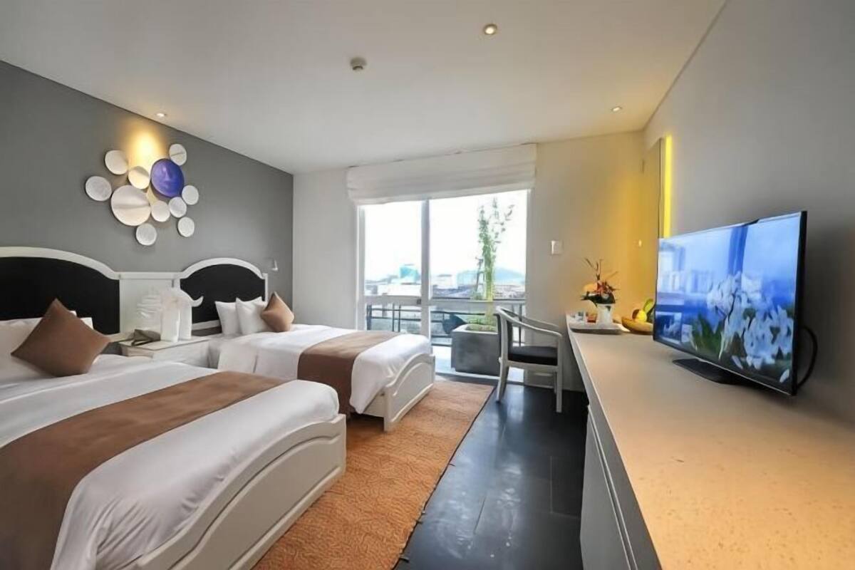 Et hotelværelse med to senge, et fjernsyn, en balkon med udsigt og moderne indretning.