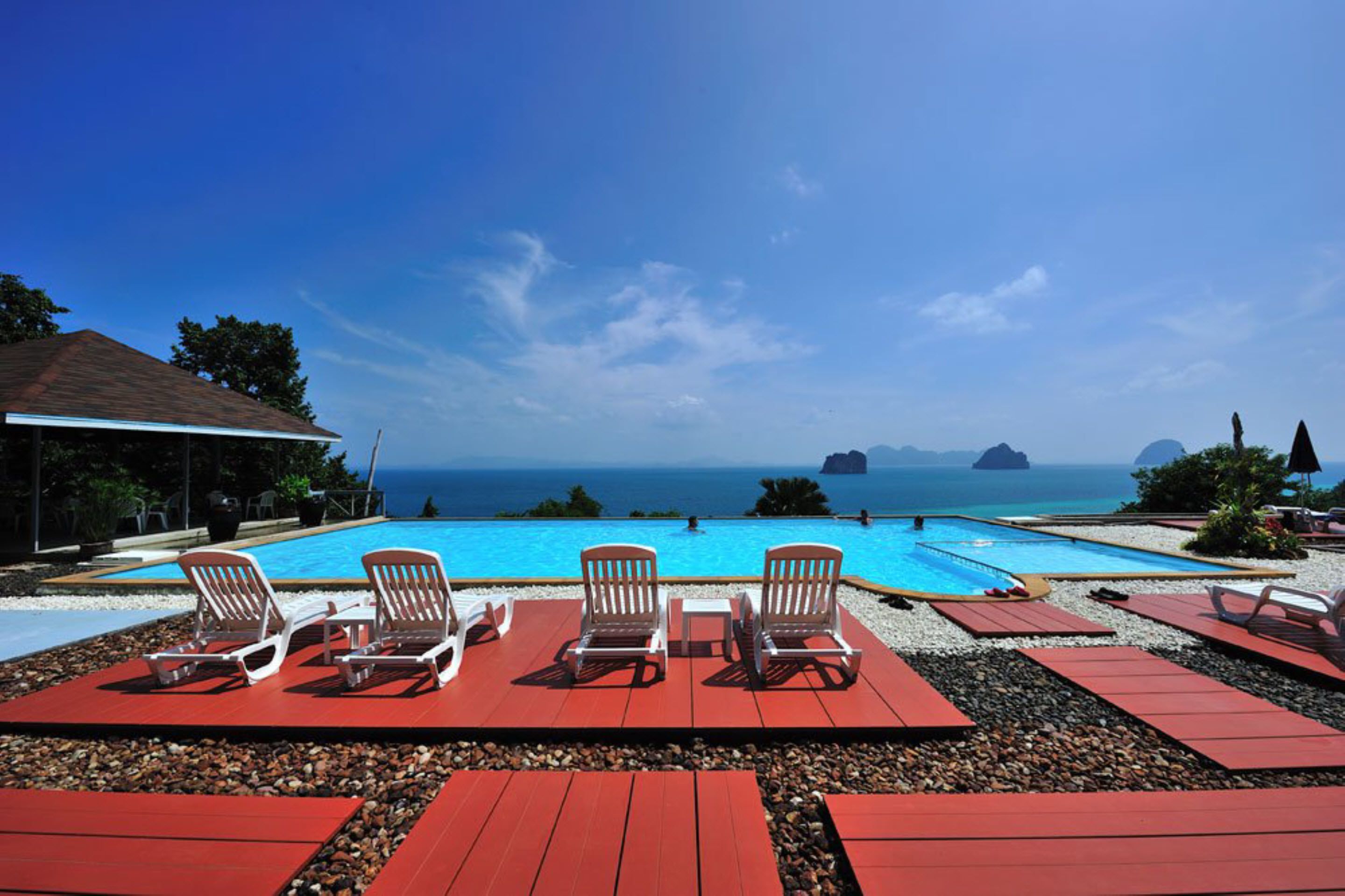 Ein Poolbereich mit Liegestühlen und Blick auf den Ozean.