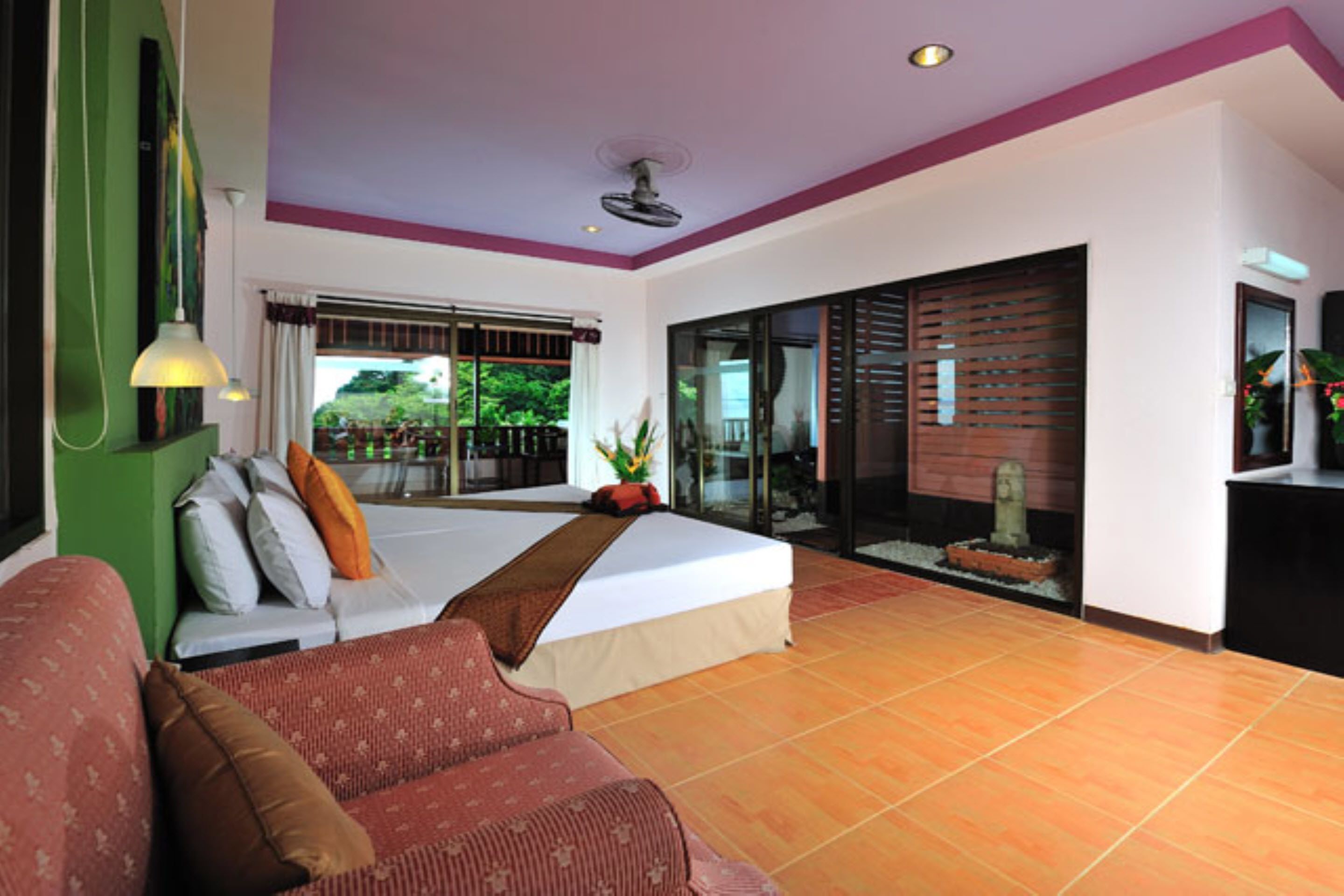 A hotel room with a bed, a sofa, a large window, and a sliding glass door leading to an outdoor area.