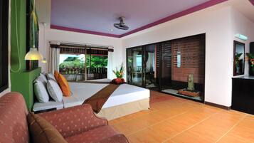 A hotel room with a bed, a sofa, a large window, and a sliding glass door leading to an outdoor area.
