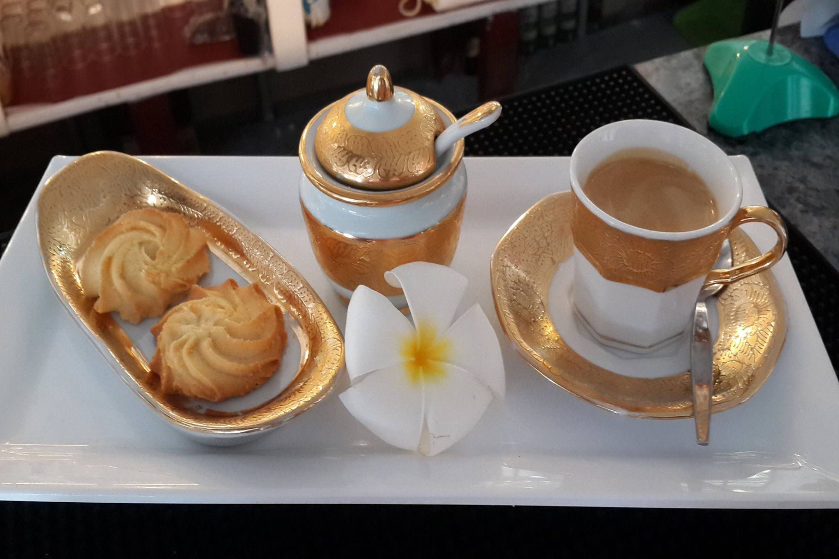 Una bandeja con pasteles, una tetera y una taza de té sobre un plato blanco.