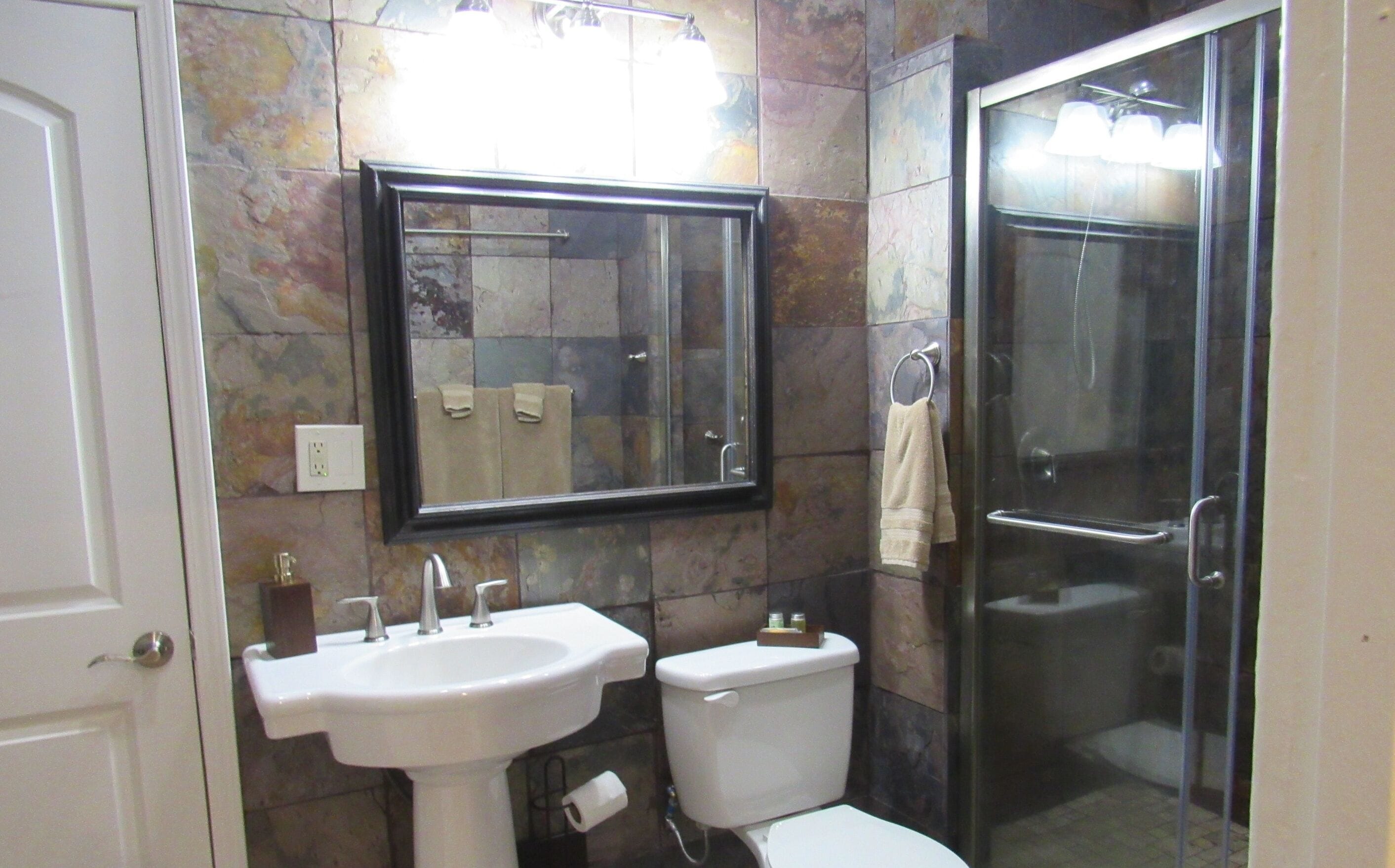 Un baño con lavamanos, inodoro y cabina de ducha de vidrio.