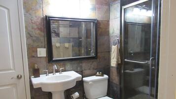 Un baño con lavamanos, inodoro y cabina de ducha de vidrio.