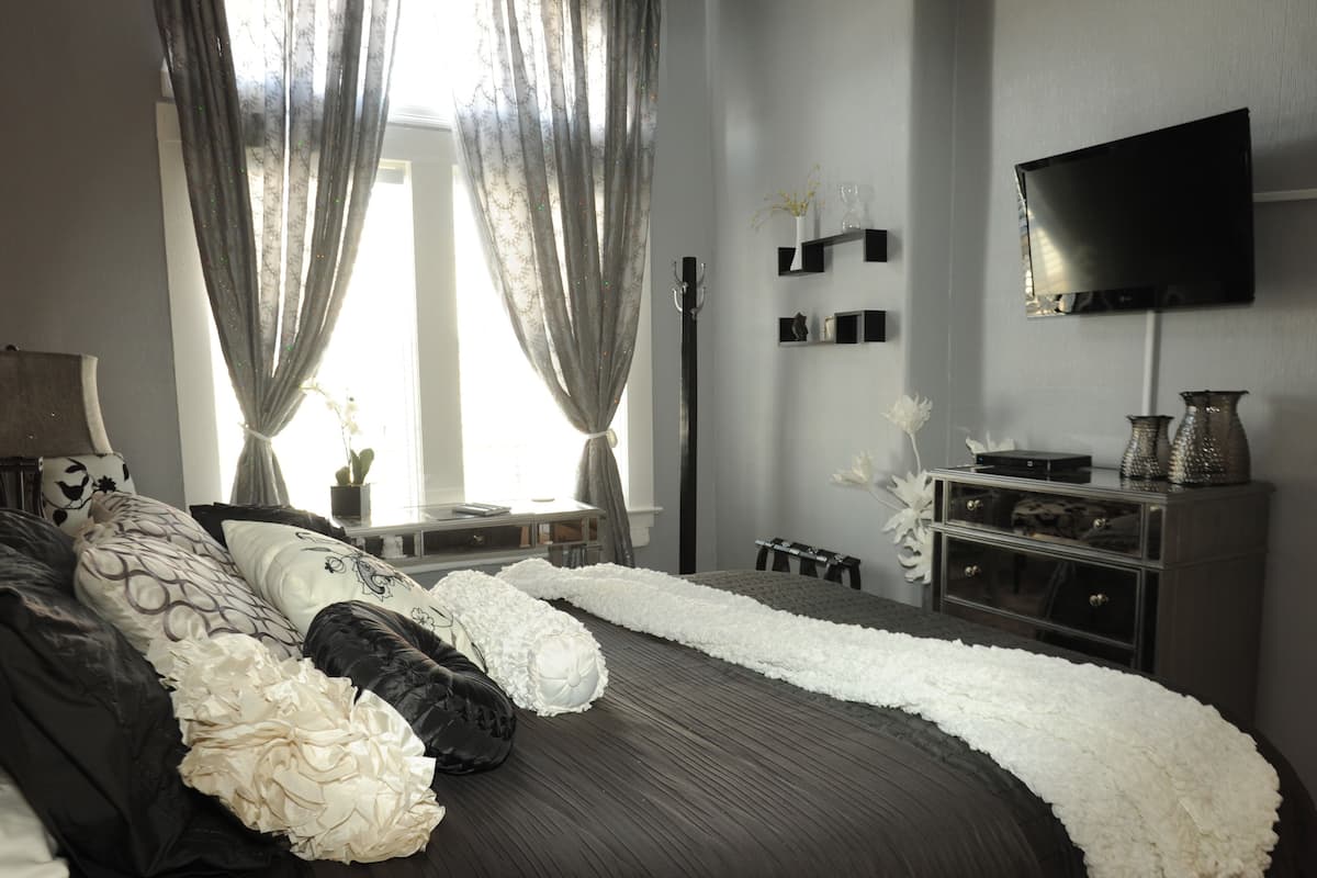 A modern bedroom with a large bed, a flat-screen TV, and a minimalist decor style.