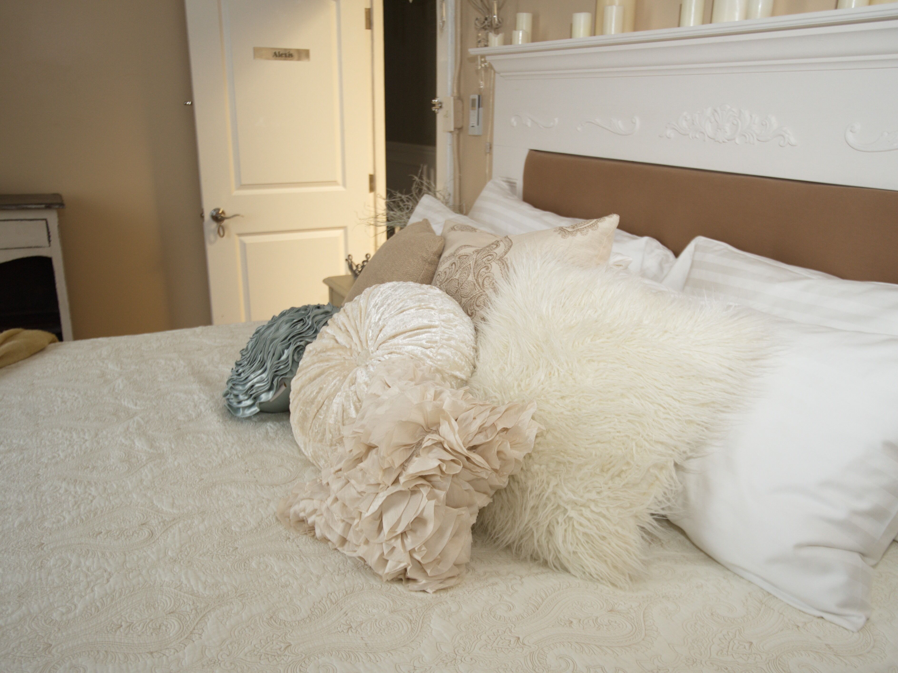 A bed with multiple pillows and a white headboard.