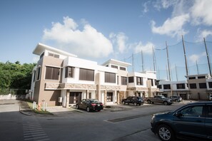 A modern multi-story residential building with a parking area in front. - Tumon Bel-Air Serviced Residence (Tamuning)