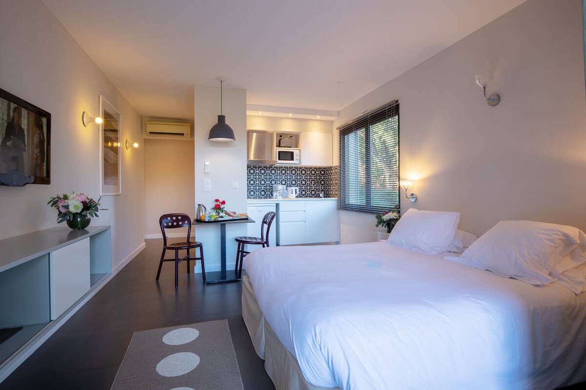 Ein modernes Hotelzimmer mit einem großen Bett, einem Schreibtisch und einer Küchenzeile.