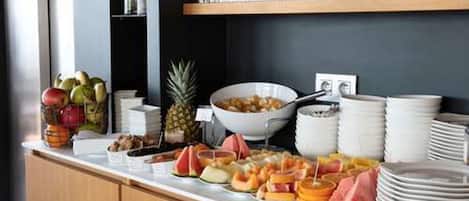 Un bufé con varias frutas y un tazón de cereal.