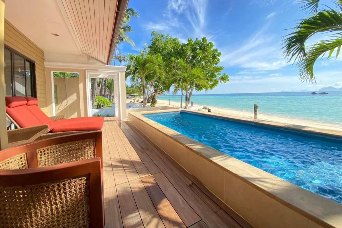 Ein Poolbereich mit Blick auf das Meer, eine Liege und ein Holzdeck.