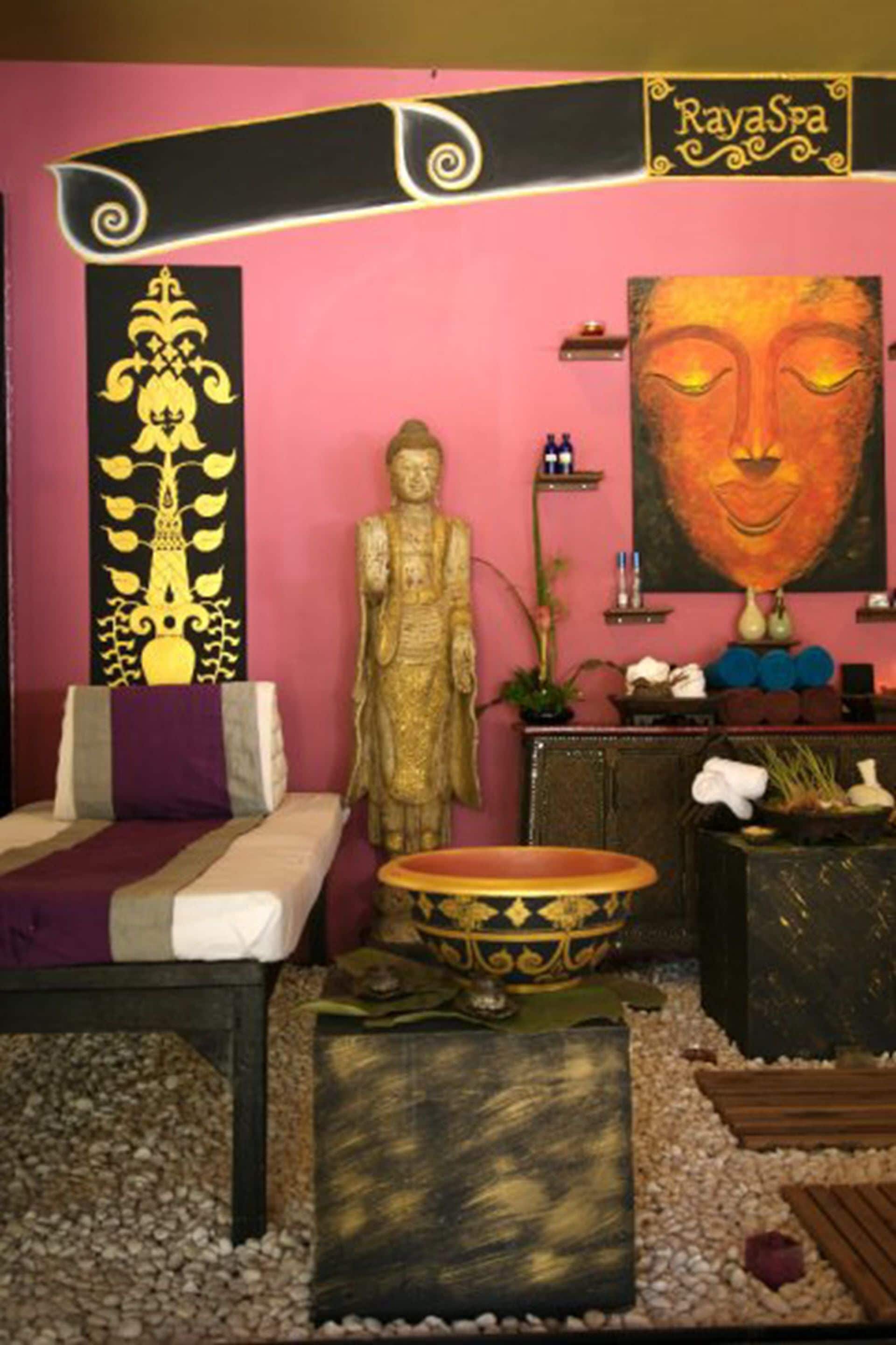 Una habitación con una estatua de Buda, una cama, una mesa de masaje, un panel decorativo y una pintura.