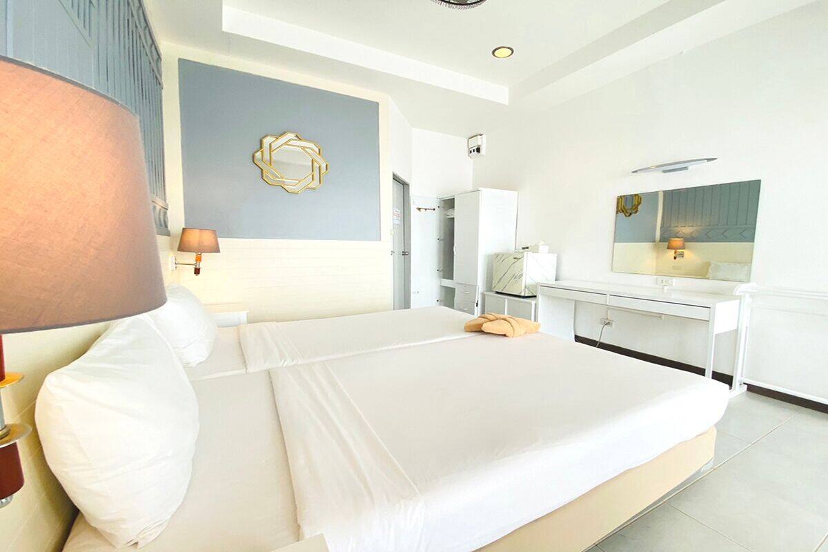 Ein modernes Hotelzimmer mit einem großen Bett, einer Nachttischlampe, einem Spiegel und einem Wandbild.