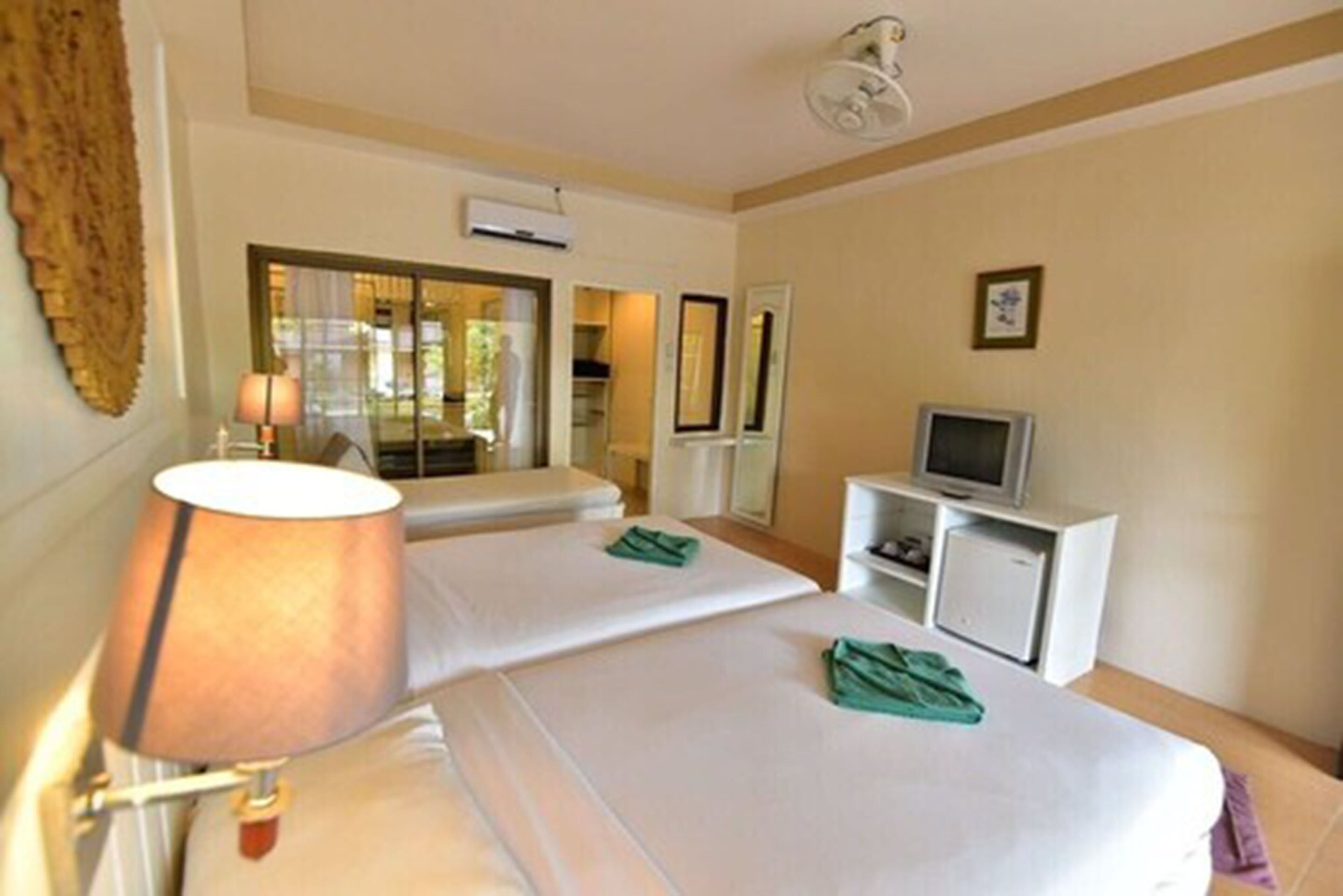 A hotel room with two beds, a TV, and a desk.