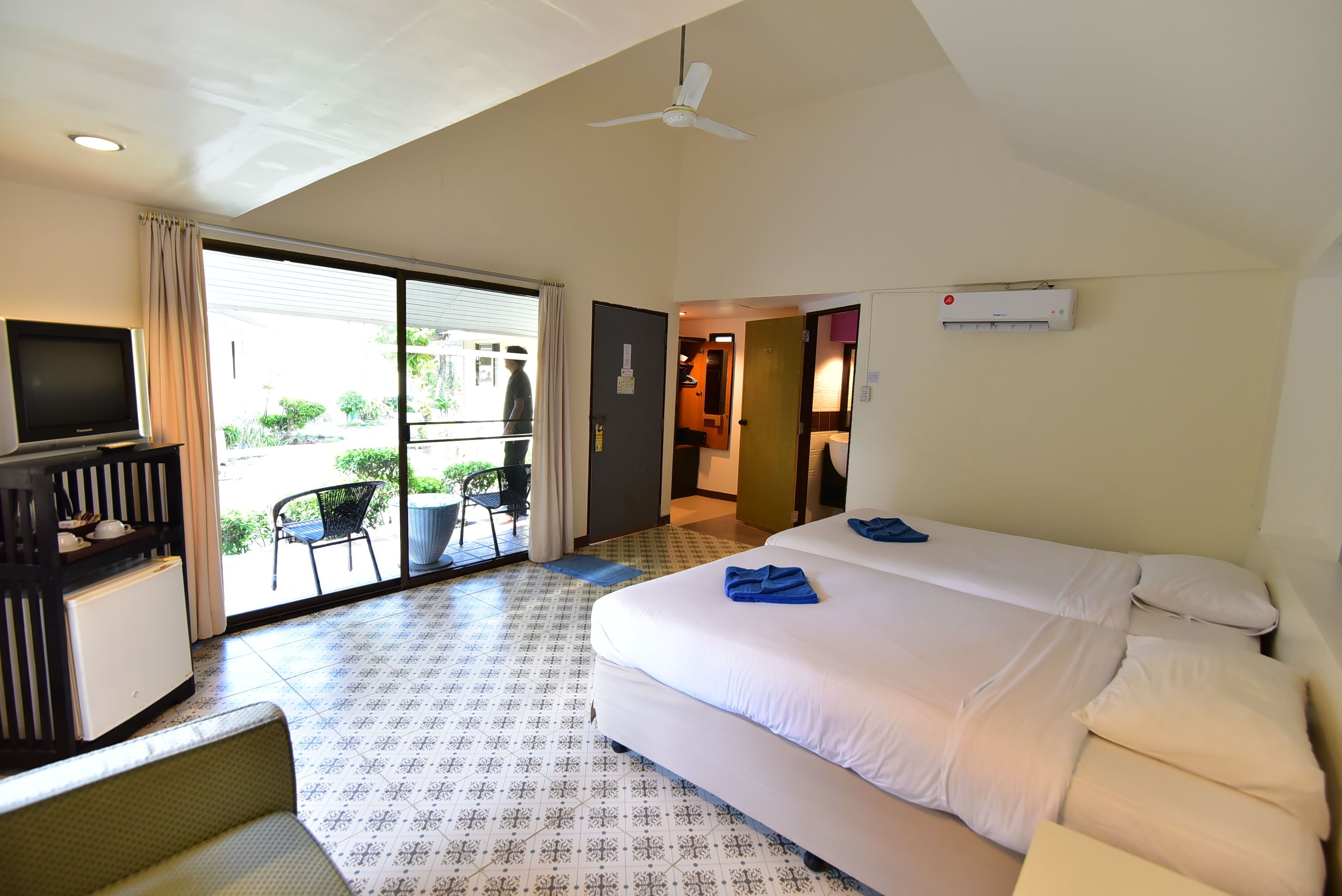 A hotel room with a bed, a TV, a desk, and a balcony.