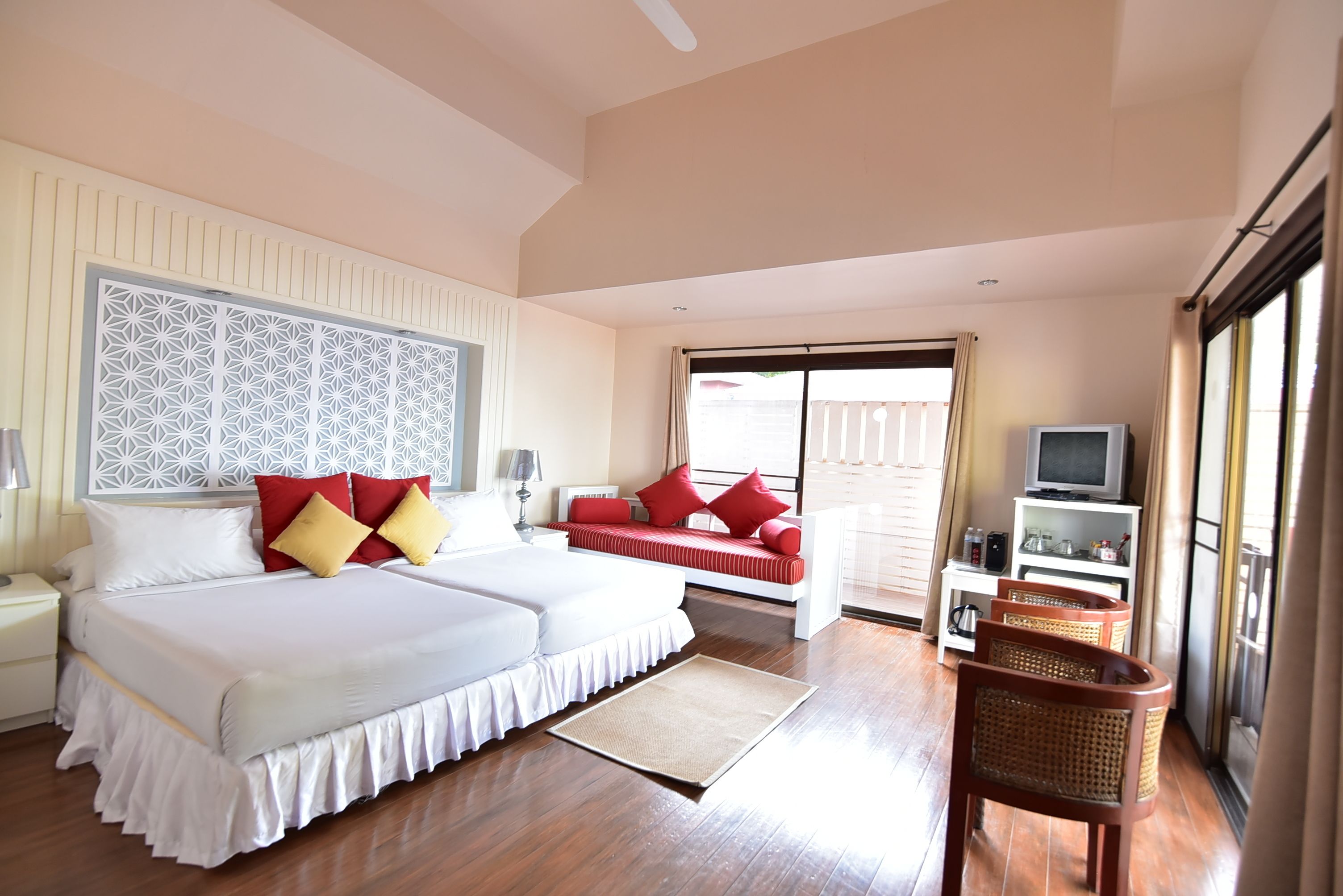 A hotel room with a large bed, a sofa, a TV, and a balcony.