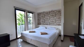 Ein Hotelzimmer mit einem großen Bett, einem Balkon mit Blick auf Palmen, einer Wand mit Steinverkleidung und einem modernen Design.