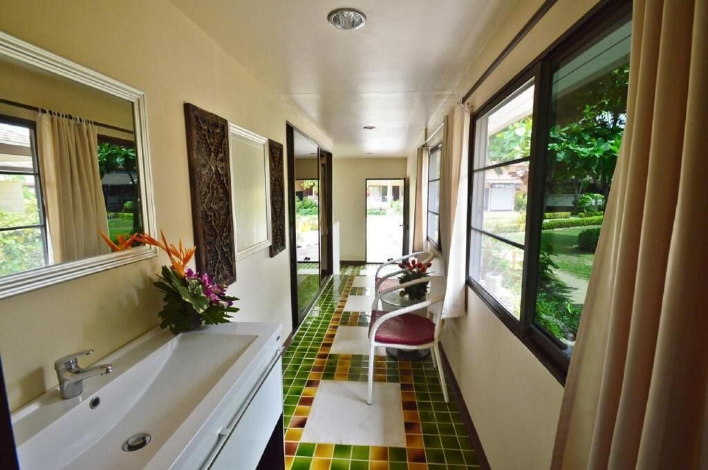 A hotel hallway with a white bathtub, a chair, and a window with curtains.