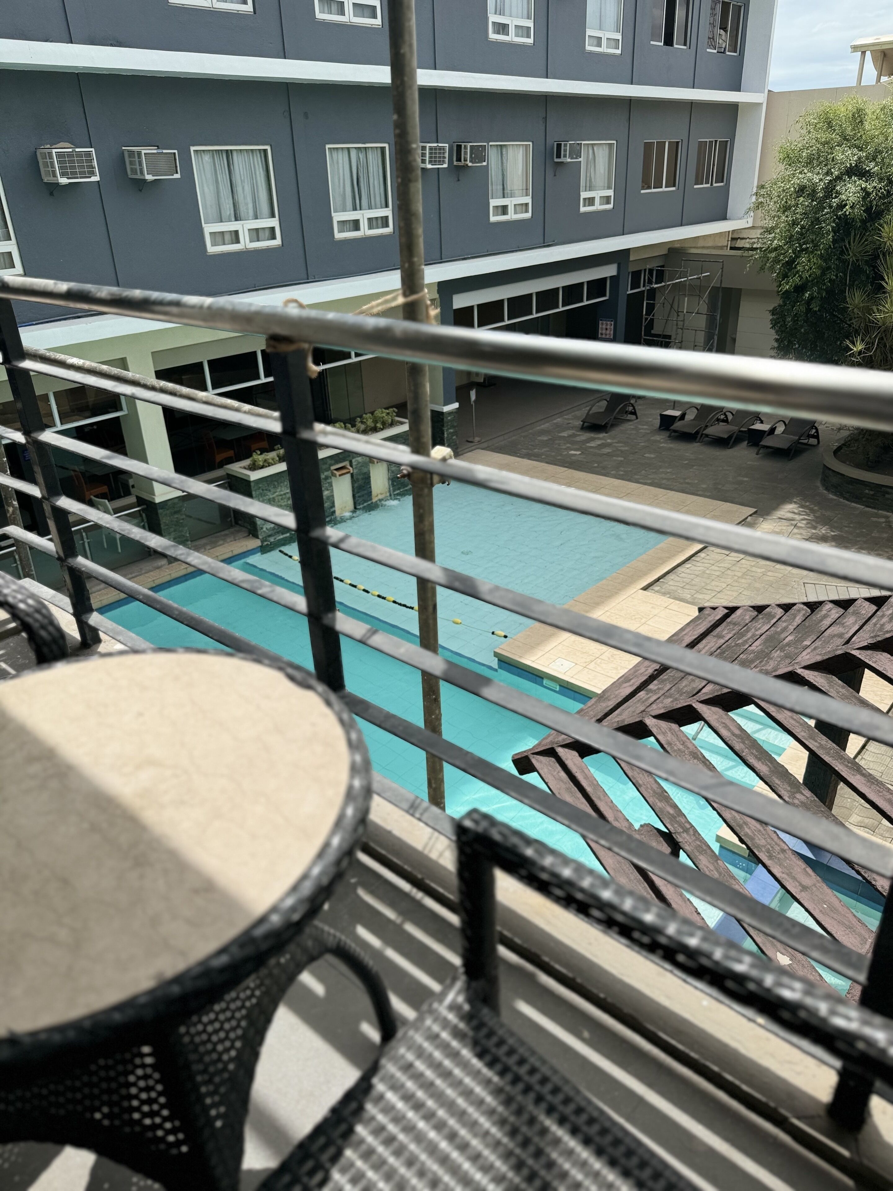 A balcony with a pool, lounge chairs, and a table.
