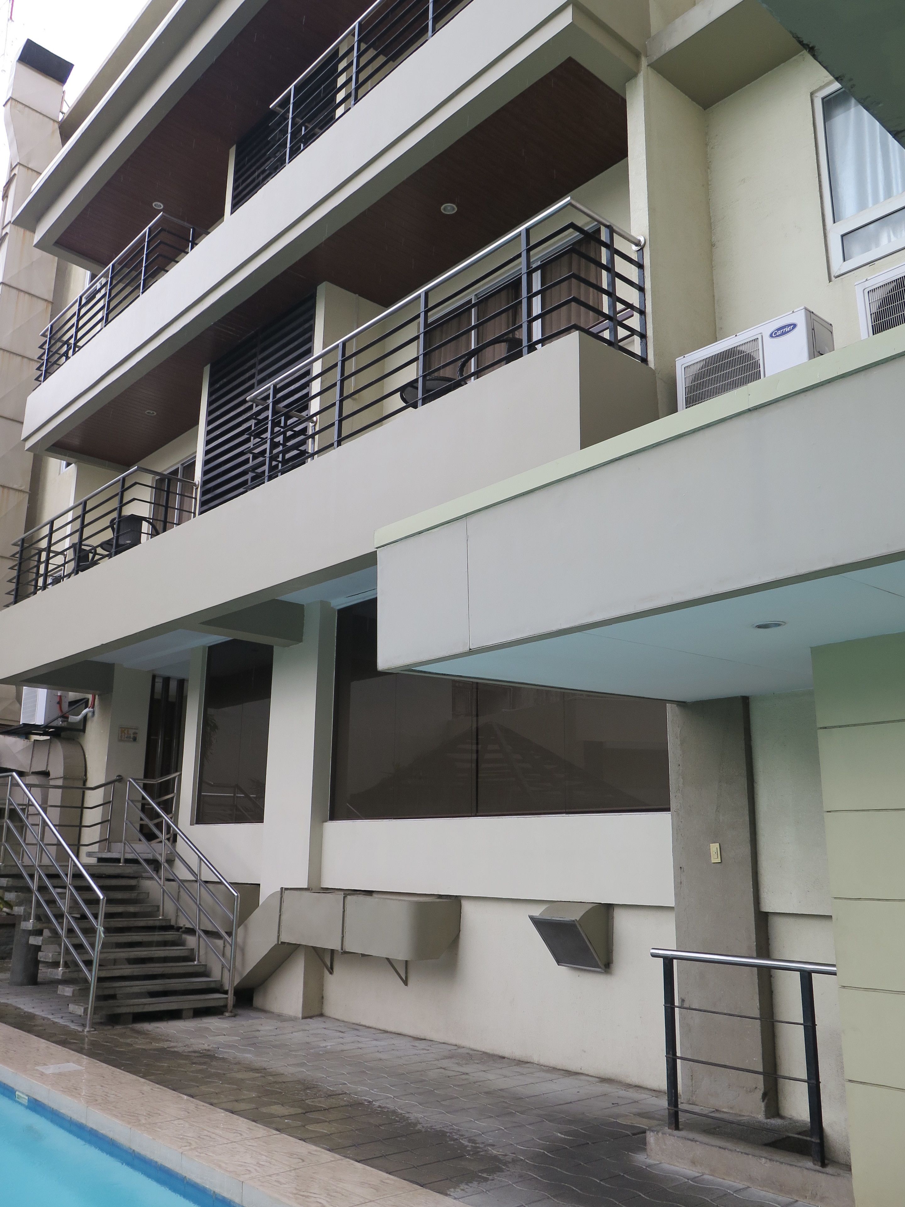 Un edificio de varios pisos con balcones, una escalera y una piscina.