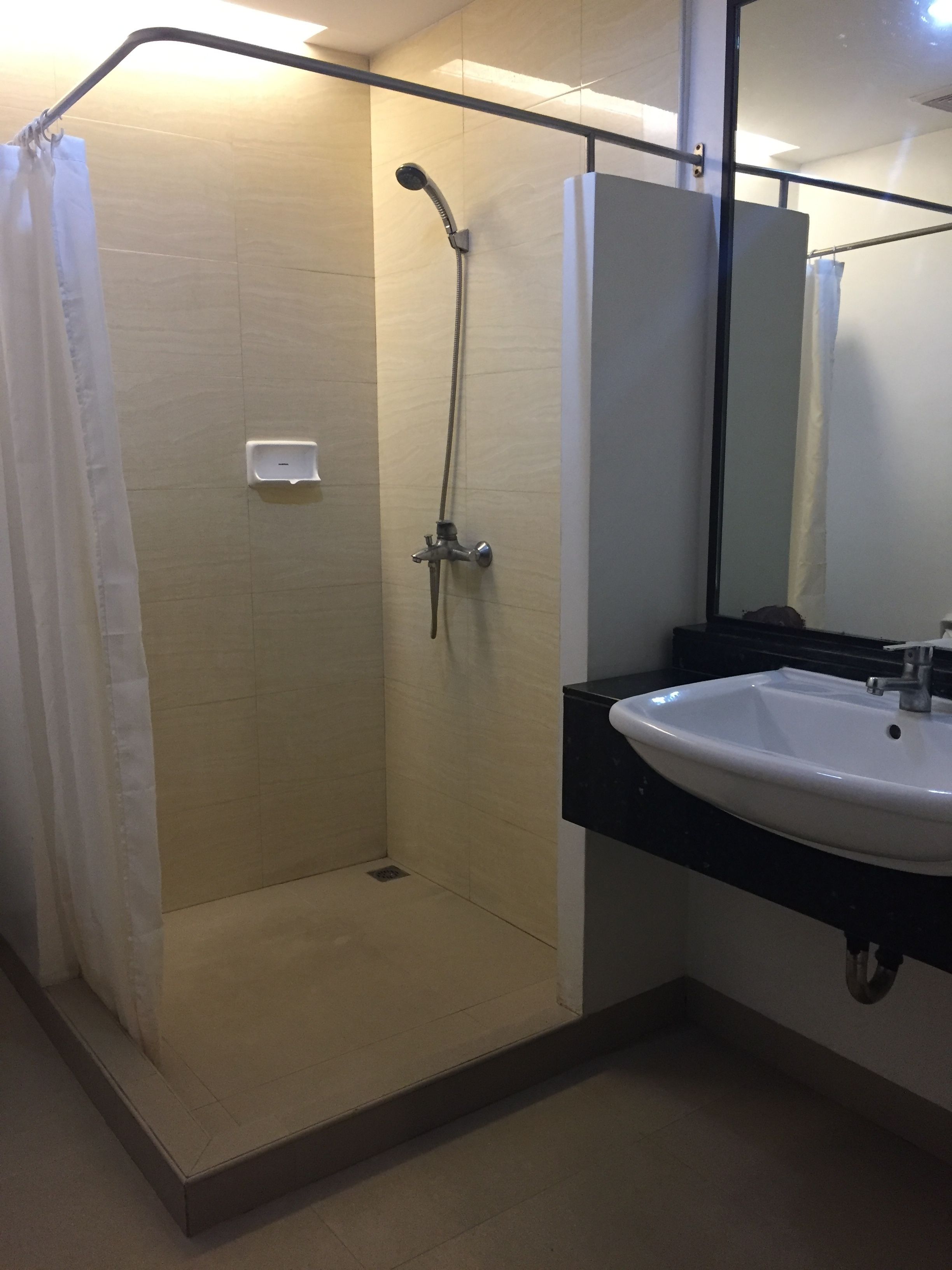 Une douche avec une porte en verre, un lavabo blanc et un miroir.