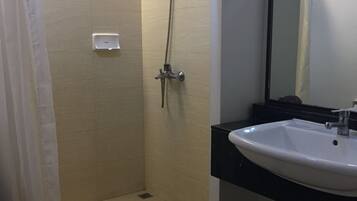 Une douche avec une porte en verre, un lavabo blanc et un miroir.
