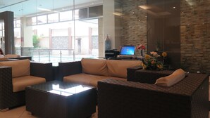 A modern lobby with a glass partition, comfortable seating, a laptop on a table, and a decorative vase with flowers. - Circle Inn - Iloilo City Center (Iloilo)