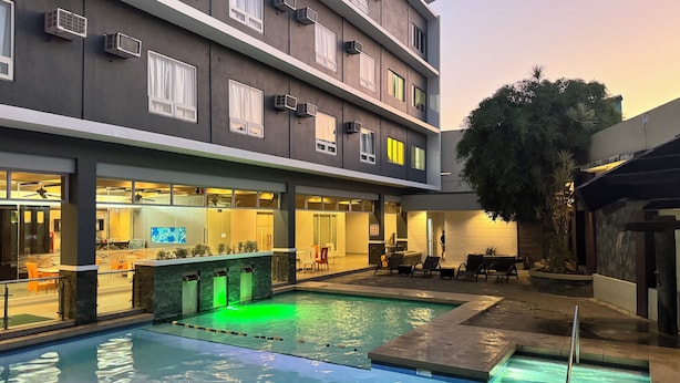 A modern hotel with a pool, outdoor seating, and a well-lit entrance. - Circle Inn - Iloilo City Center (Iloilo)
