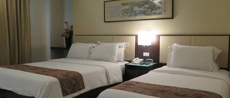 A hotel room with two beds, a nightstand with a phone and clock, a framed artwork on the wall, and a vase with flowers.
