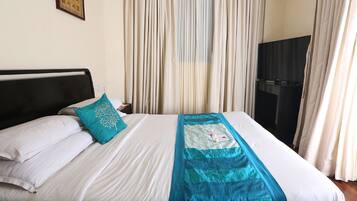 Una cama bien hecha con ropa de cama blanca y aguamarina, cabecera negra y almohada decorativa color aguamarina.