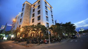 A multi-story hotel with a white facade and illuminated signage. - Chu Hotel (Da Nang)