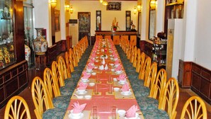 A long dining table set with chairs, a reception desk, and decorative elements. - Areca Hotel (Hue)