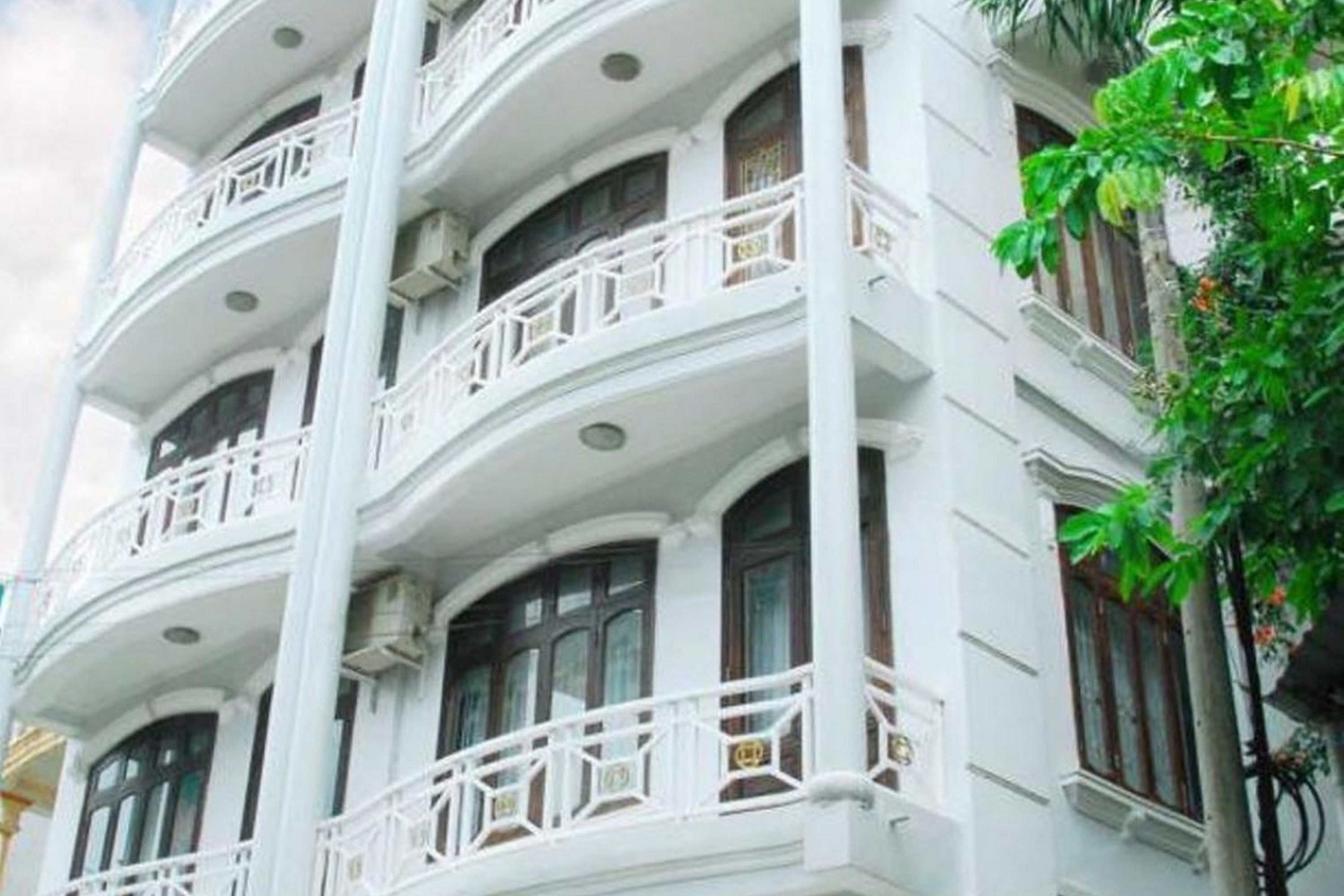 A multi-story building with white balconies and dark wooden doors.