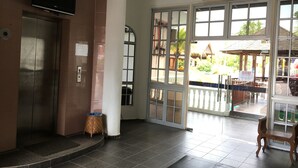 An interior space with a tiled floor, a television mounted on the wall, a trash bin, and a bench. - Landcons Hotel (Langkawi)