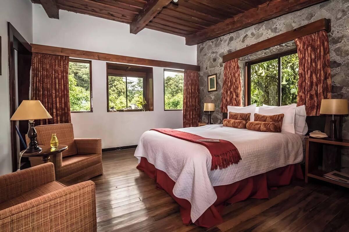 Un dormitorio espacioso con una cama grande, suelo de madera y una pared de piedra decorativa.