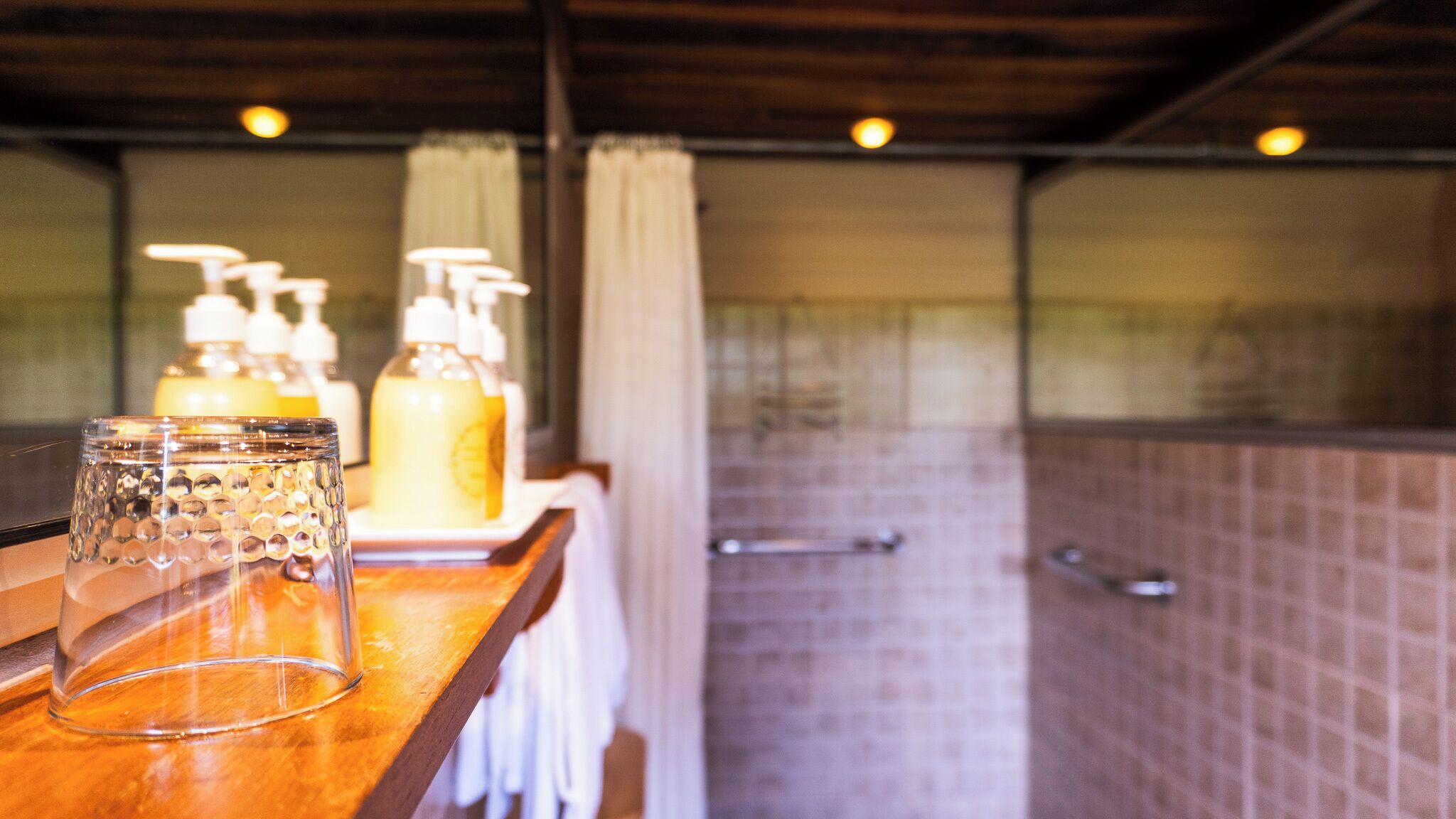 A bathroom with a wooden counter, a glass container, and toiletries.