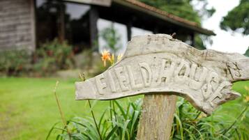 A wooden signpost with the inscription "FIELD HOUSE" in a garden setting.