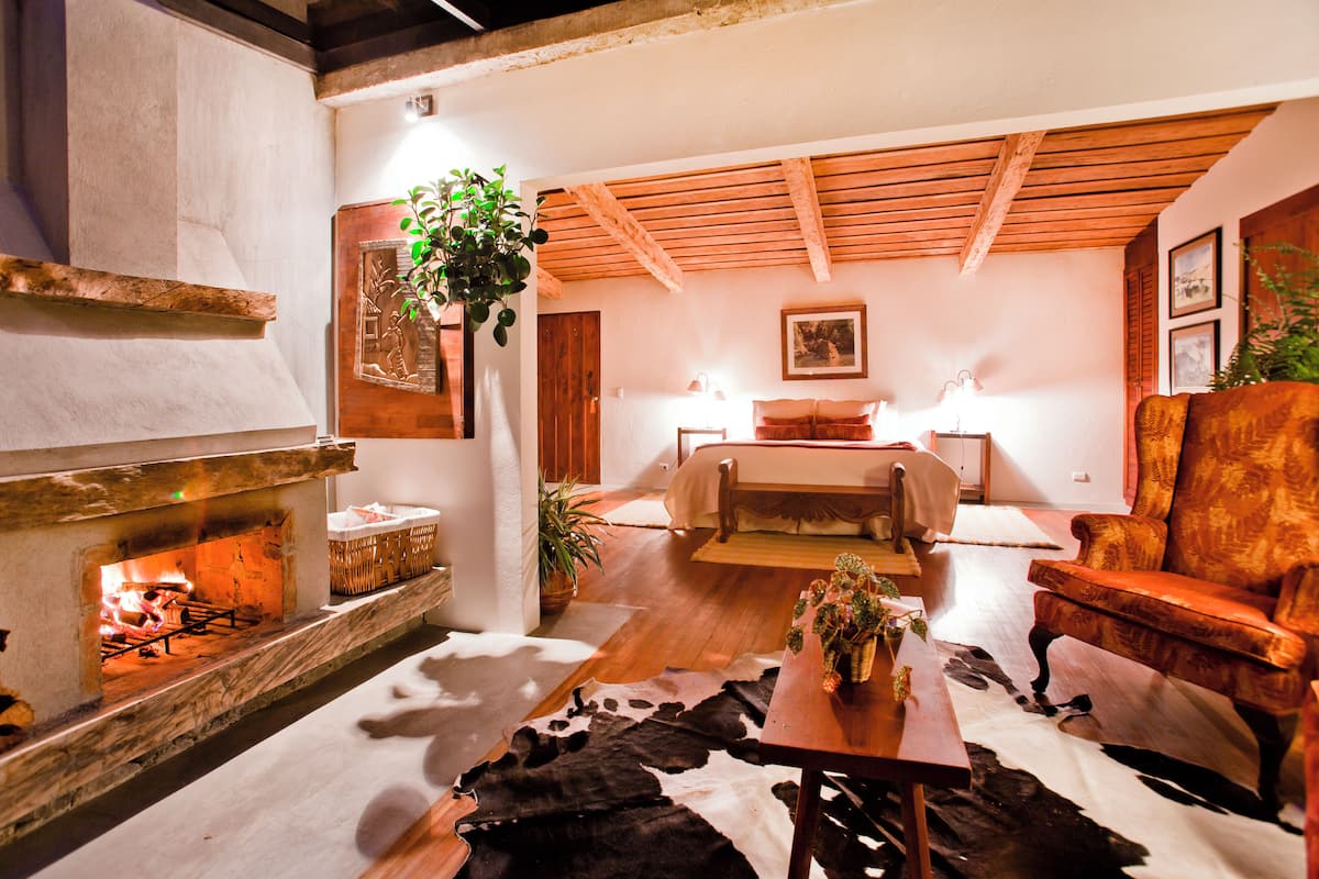 Una habitación acogedora con chimenea, una cama, un sofá y una alfombra de cuero de vaca.