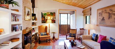 A cozy living room with a fireplace, wooden floors, and a variety of seating options including a sofa and chairs.