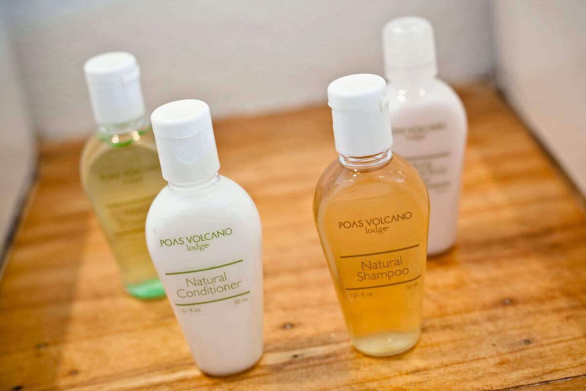 Four bottles of POAS VOLCANO lodge natural products on a wooden surface.