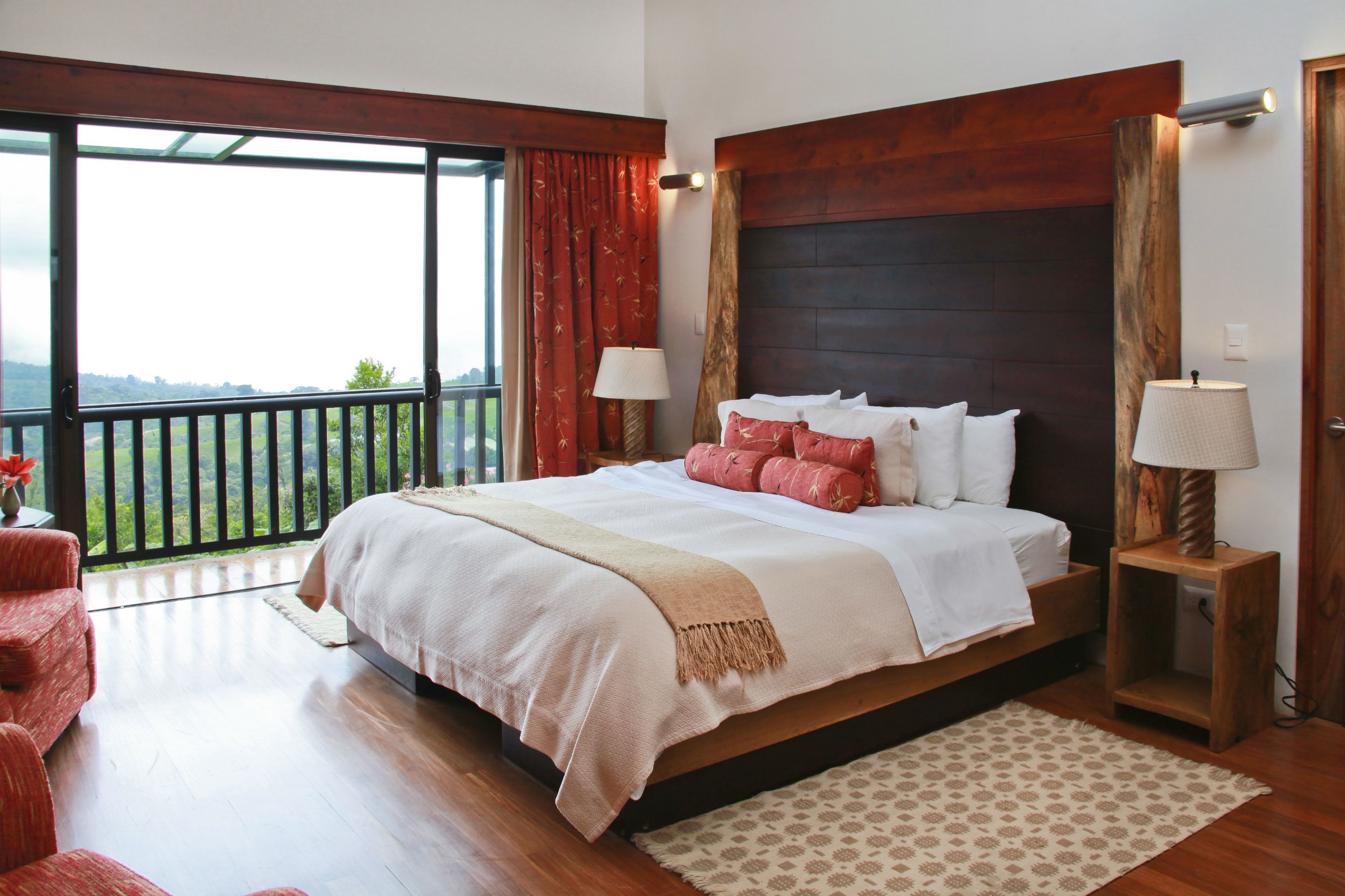 Un dormitorio amplio con una cama grande, un balcón y vistas al exterior.