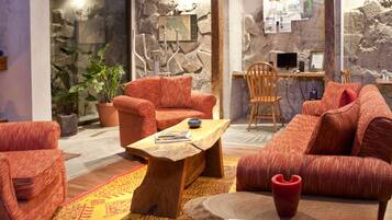 A cozy living room with red upholstered furniture, a wooden coffee table, and a stone wall with a map.