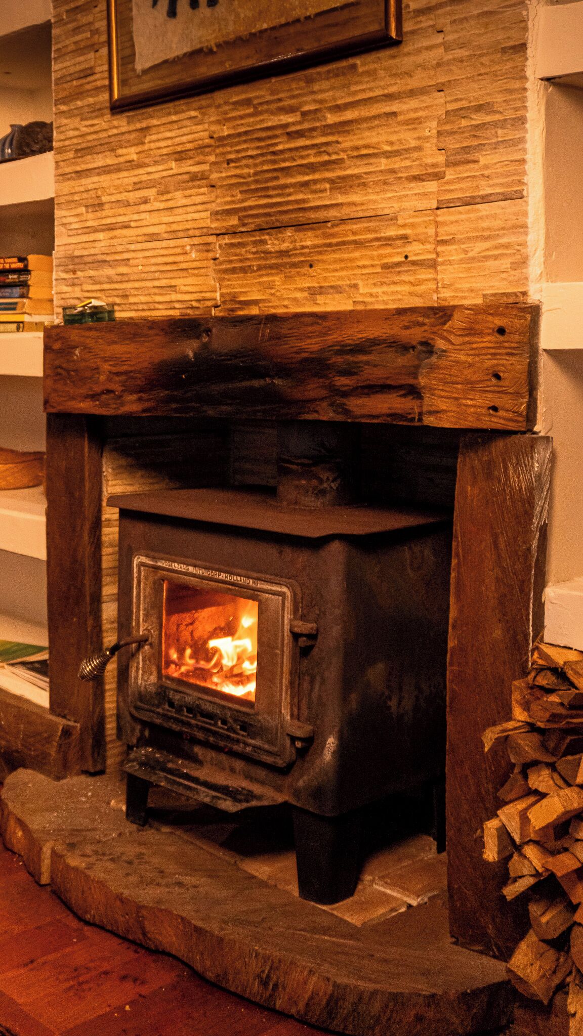 A wood-burning stove with a fire burning inside, set in a stone fireplace.