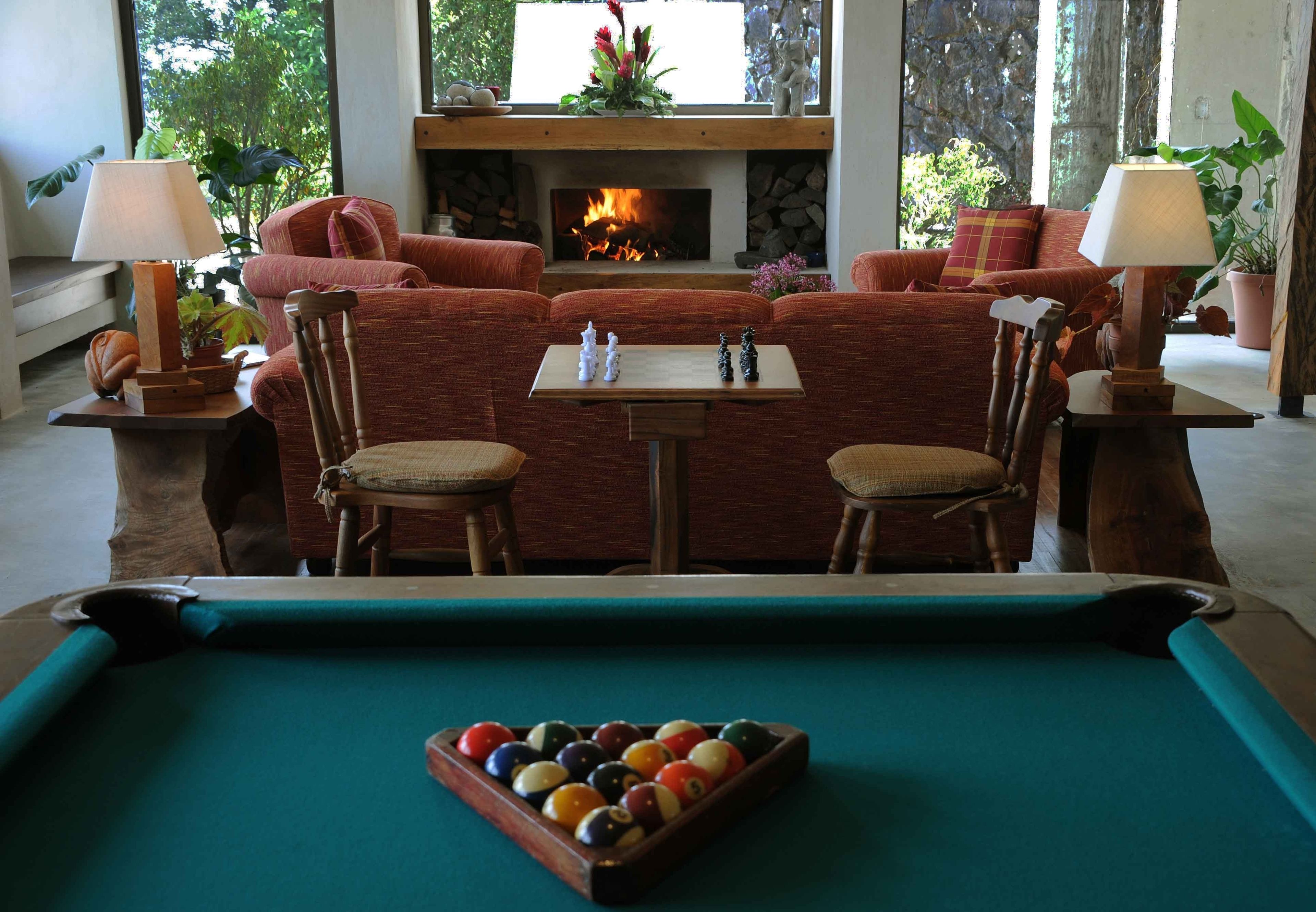 Una mesa de billar con bolas, una chimenea, un conjunto de sofás y dos lámparas.