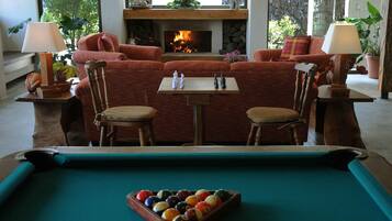 Una mesa de billar con bolas, una chimenea, un conjunto de sofás y dos lámparas.