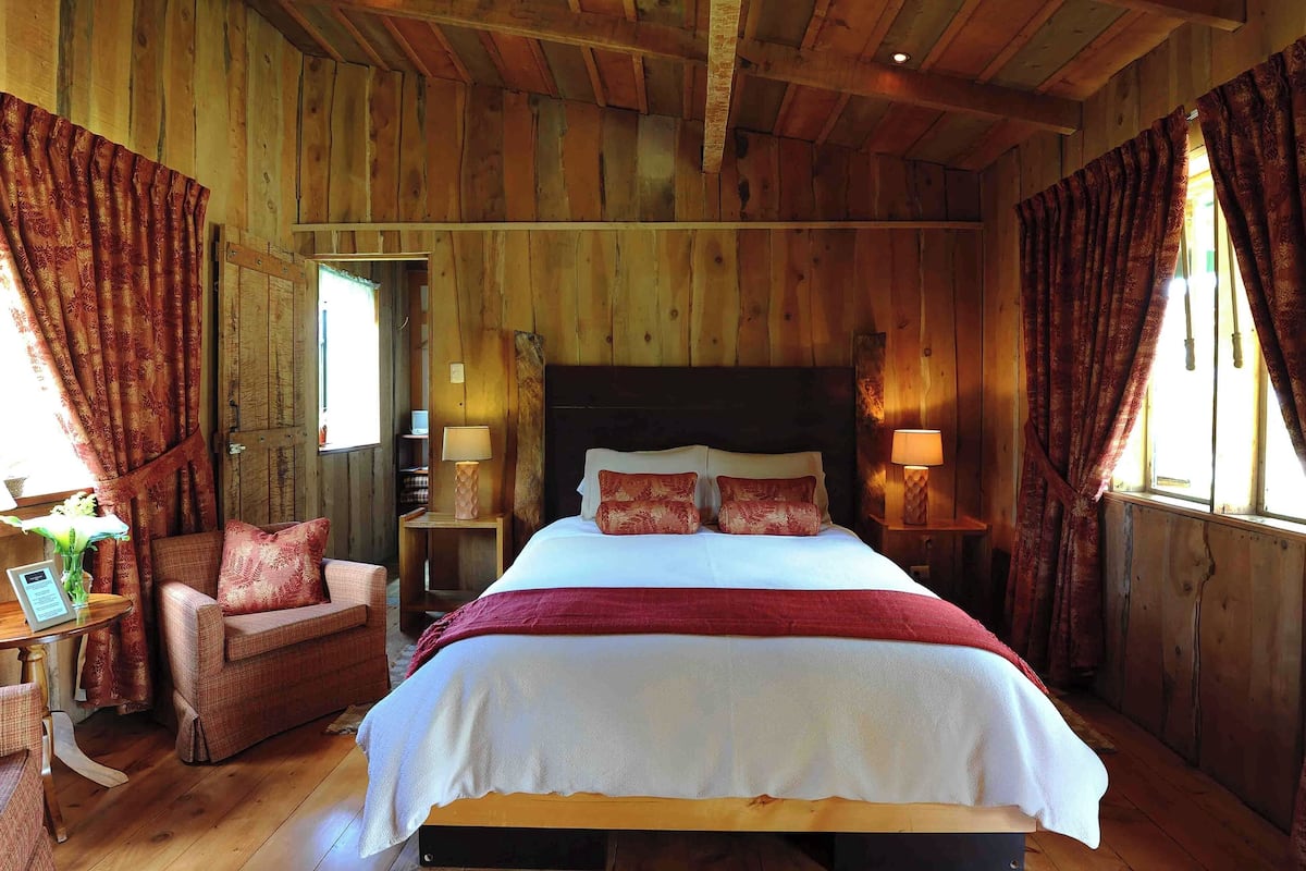 Un dormitorio de cabaña de madera con una cama, una silla y una mesa.