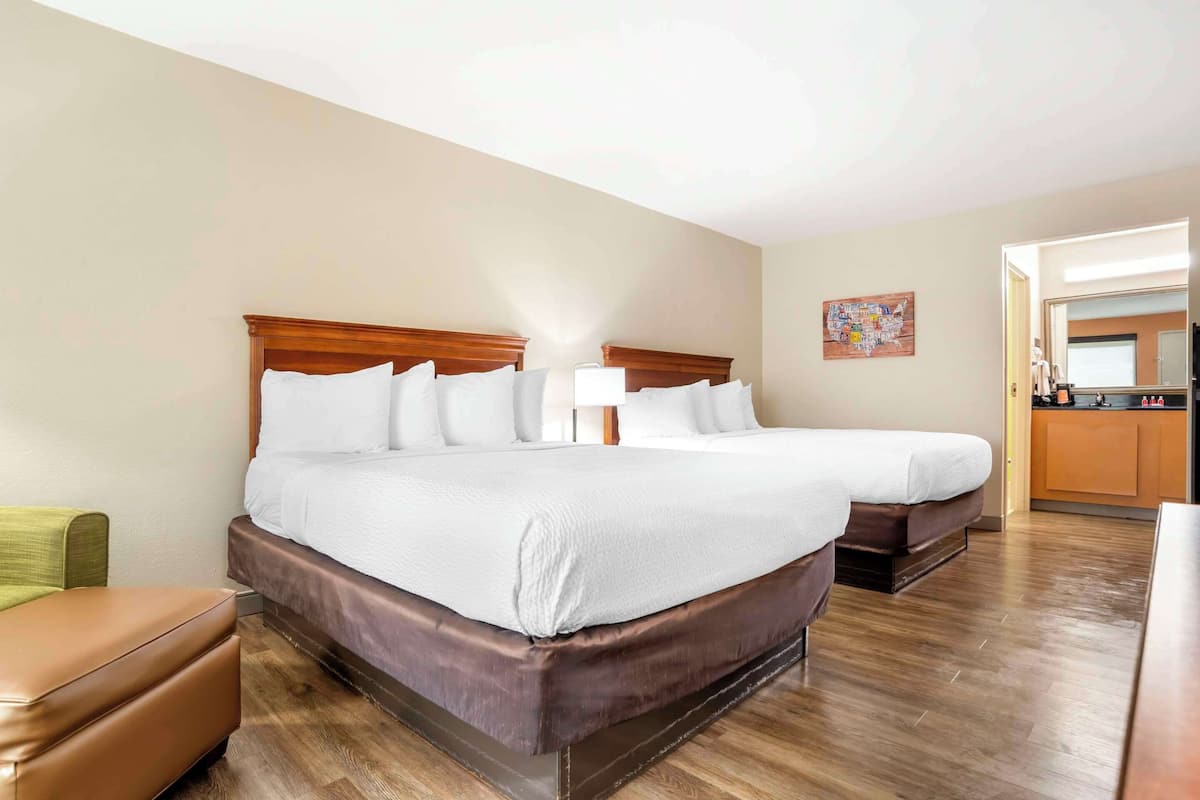 A hotel room with a large bed, a small sofa, and a kitchenette.