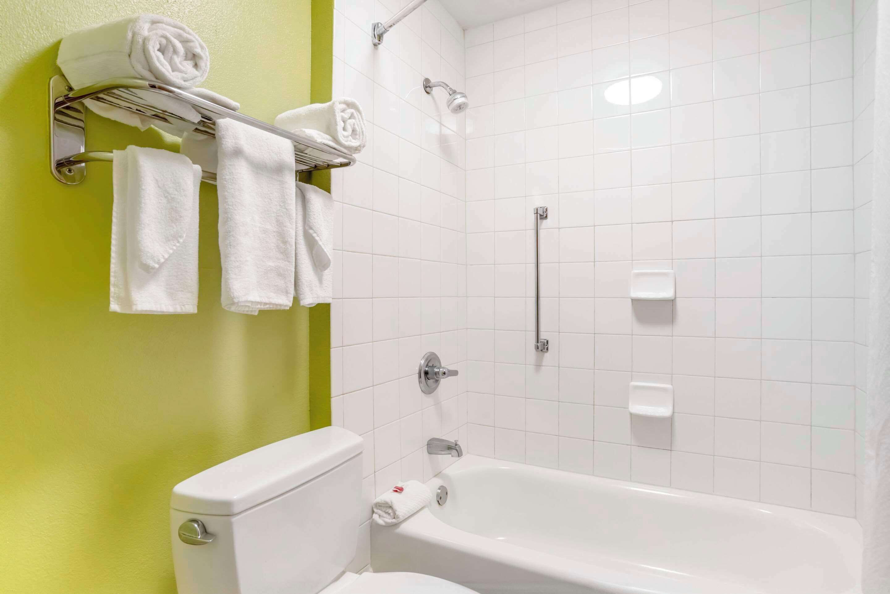 Un baño con una bañera blanca, un inodoro y un perchero con toallas.